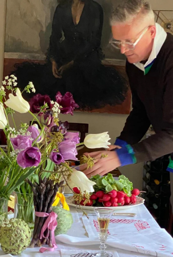 Giles Deacon arranging flowers next to his designs on luxury embroidered linen