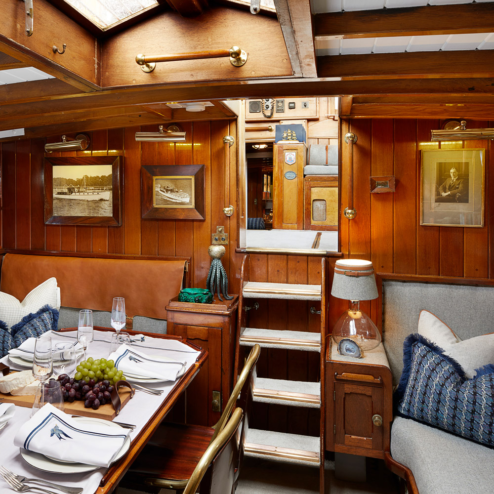 Inside the Bluebird of Chelsea boat cabin, elegantly designed table cloths embroidered with intricate designs by Peter Reed